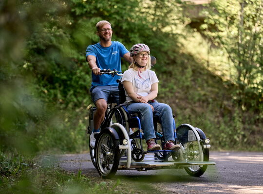 Mitarbeiter fährt ein Mädchen auf einem Spezialfahrrad
